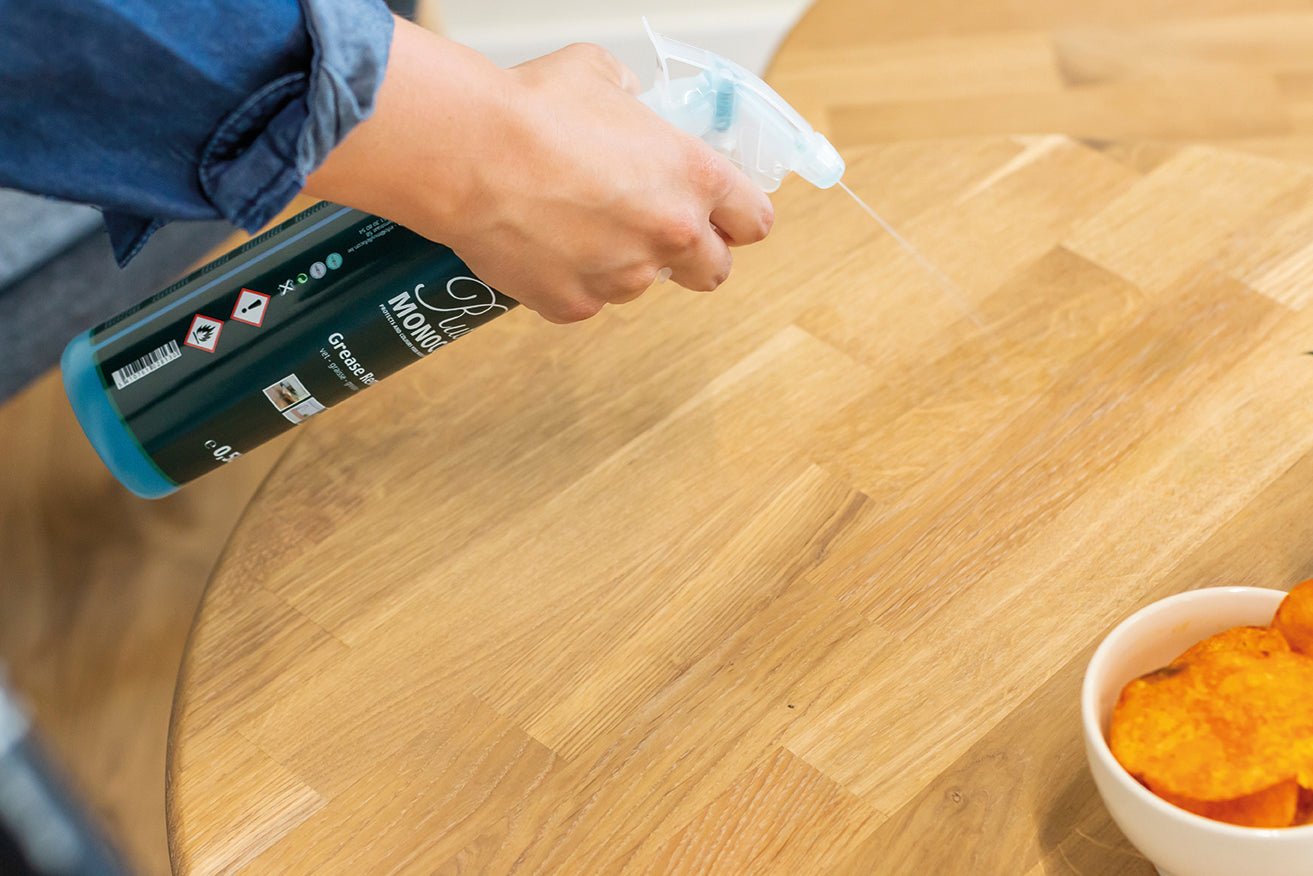 Person using Grease Remover on a wooden surface.