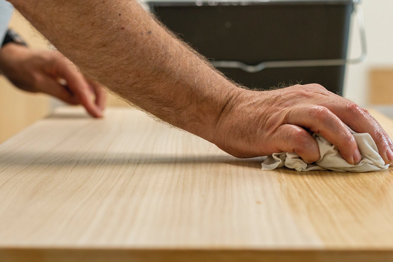 Person cleaning a wooden surface with a cloth.